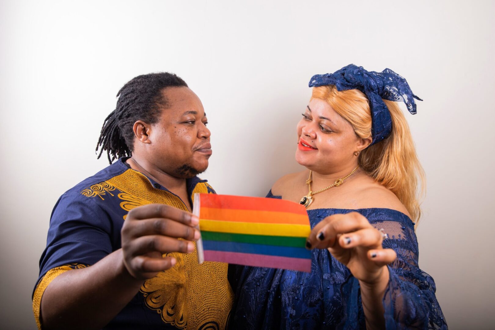 A man and woman holding up a rainbow flag.